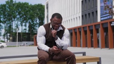 Pozitif Afro-Amerikan karışık ırkının portresi. Afro adam serbest çalışan işadamı cep telefonuyla konuşuyor. Şehirde oturan siyahi adam çağrıya cevap veriyor..
