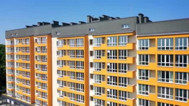 Şehir sakinleri için yeni bir evin ön cephesi. Güneşli yaz gününde geniş pencereli ve renkli duvarlı modern apartman..