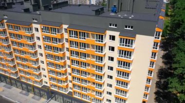 Modern tasarımın yeni yüksek binası. Turuncu renkli geniş balkonlu çok katlı bir bina. Hareket kamerası aşağı.