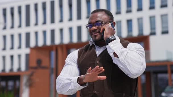 一个身强体壮的非洲人在城市里讲电话 成功的黑皮肤商人与城市背景的电话交谈 — 图库视频影像