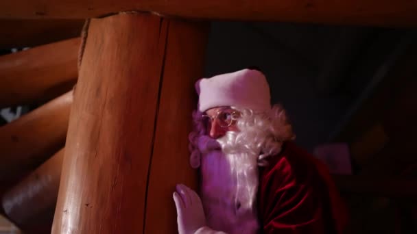 木造の家に隠れているサンタクロース 木柱から見たプレゼント付きのサンタと白ひげと赤い衣装 — ストック動画