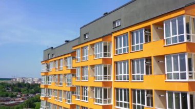 Şehirde yeni bir çok katlı bina. Turuncu duvarlı, geniş balkonlu bir apartmanın modern tasarımı. Şehir sakinleri için lüks ev cephesi.