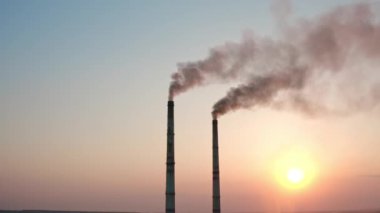 Açık gökyüzü arka planında duman boruları. Fabrika bacaları atmosfere karanlık emisyonlar salar. Kimyasal duman havayı kirletir. Ekoloji tehlikede.