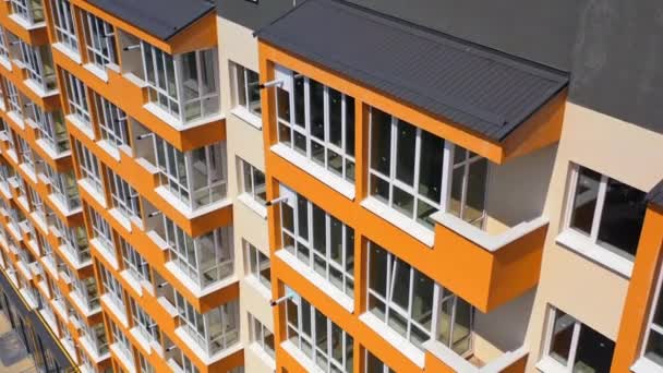 新的城市多层建筑 灰色的屋顶和明亮的橙色墙壁 有现代化公寓楼的大阳台 上下左右移动相机 — 图库视频影像