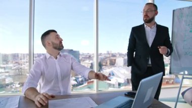 İş adamları modern ofis merkezinde çalışır. İş ortakları yeni planlar hakkında konuşuyor. Şehir arka planına sahip panoramik pencereler.