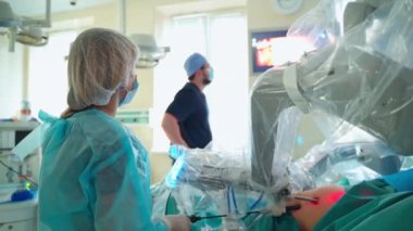 Ameliyat sırasında hastanın karnındaki robot kol. Cerrah, modern klinikteki monitör ekranında robotik operasyon sürecini gözlemliyor. Yenilikçi tıp. Yakın plan..