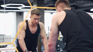 Spor salonundaki ayna yansıması sporcusu. Yakışıklı sporcu sıkı çalışmadan sonra dinlenir. Kaslı vücut geliştirici içeride..