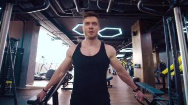 Atletik adam modern bir simülatörde kas çalıştırıyor. Modern spor salonundaki yakışıklı sporcunun portresi. Sporcu mükemmel vücudunda yoğun bir şekilde egzersiz yapar..