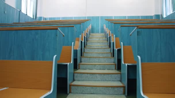 空っぽの講堂 カンファレンスホールの2列のデスクの間の階段 学生なしで勉強するための美しいクラス 木製の机のある大学の教室 — ストック動画