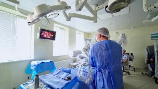 医師はロボット手術を行い スクリーンを見ています 現代的な医療機器を備えた外科室 手術用ロボットを使用したプロ外科医 — ストック動画