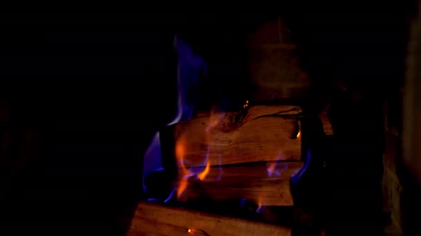暗い背景に青い炎の木が燃えています ファイアウッドは暖炉で燃え始めている 木製の木製の木は 石の暖炉で燃え始めています クローズアップ — ストック動画