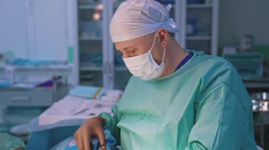 Cerrah estetik ameliyat yapıyor. Klinikte ameliyat sırasında cerrahi makasla çalışan tıbbi maske ve üniformalı profesyonel doktor..