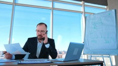 Ofiste telefonla konuşan kendine güvenen bir iş adamı. Bir patronun portresi masada oturuyor ve telefonda iş sorunları ile uğraşıyor..