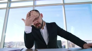 Ofiste oturan bir iş adamının portresi. Sakallı, takım elbiseli ve gözlüklü girişimci pencere arkasında iş hakkında konuşuyor..