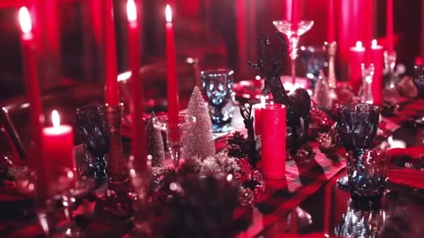 赤い色のクリスマステーブルの装飾 メガネと赤キャンドルでお祝いのテーブル 冬の光沢のある季節の装飾が施された美しいディナーテーブル — ストック動画