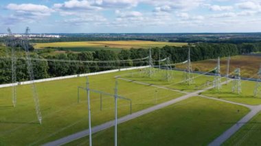 Yeşil alandaki elektrik iletim kuleleri. Elektrik hatları kablolarla dolu. Kırsalda yüksek voltajlı elektrik direkleri.