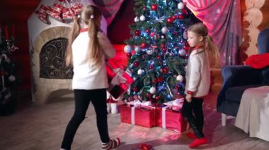 Çocuklar Noel ağacının altına hediye kutuları koyarlar. Noel hediyelerini Noel ağacına taşıyan küçük kızlar. Noel süslemeli odada çocuklar.