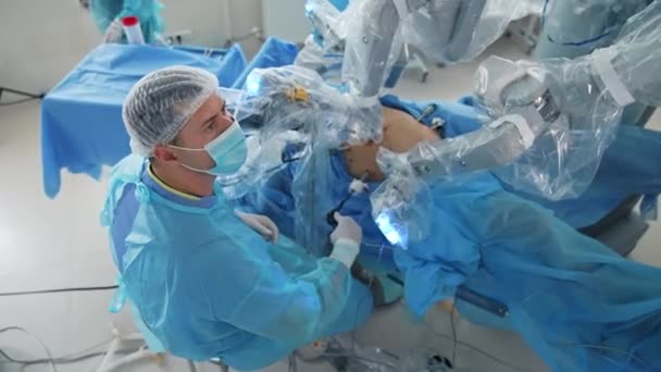 机器人技术设备的外科程序 外科机械臂在未来主义手术室做微创手术 专业医生与医疗机器人 顶部视图 — 图库视频影像