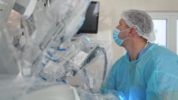 ドクターはロボット装置を使って手術を行う 近代的なオペレーティングルームの医療ロボット 専門の外科医はスクリーンの外科ロボットの仕事を観察します — ストック動画