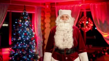 İçeride Noel Baba kostümü giymiş son sınıf bir adamın portresi. Ciddi Noel Baba 'nın beyaz sakallı hali Noel ağacı arka planında duruyor. Noel ruhu.