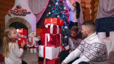 Noel 'de mutlu bir aile. Baba ve kızları parlak kutulardaki hediye yığınının yanında. Mutlu çocuklar evde Noel hediyeleriyle eğlenirler..