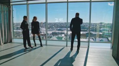 Güzel genç bayanlar ve iş adamları içeride. İş kadınları ve yakışıklı girişimciler tatilde ofis pencerelerinde duruyorlar.