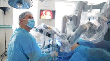 Ameliyat sırasında robot makinenin yanında profesyonel bir doktor. Tıbbi monitörler ameliyathanedeki cerrahi prosedürü gösteriyor..