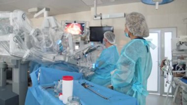 Yenilikçi ekipmanlı ameliyat. Robot kollu fütüristik makineler minimal invaziv ameliyatlar gerçekleştiriyor. Doktorlar tıbbi monitörde robot ameliyatını gözlemliyor..