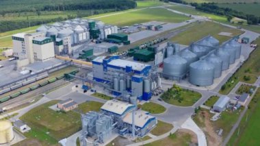 Yeşil doğa geçmişi olan çağdaş bir fabrika. Ürünleri kurutmak ve depolamak için tahıl asansörleri. Sahada yeni endüstri. Hava görünümü.