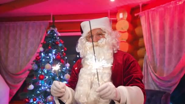 圣诞老人在室内的圣诞树背景 一个真正的圣诞老人的画像 留着白胡子 手里拿着闪亮的灯 看着镜头 新年快乐 — 图库视频影像