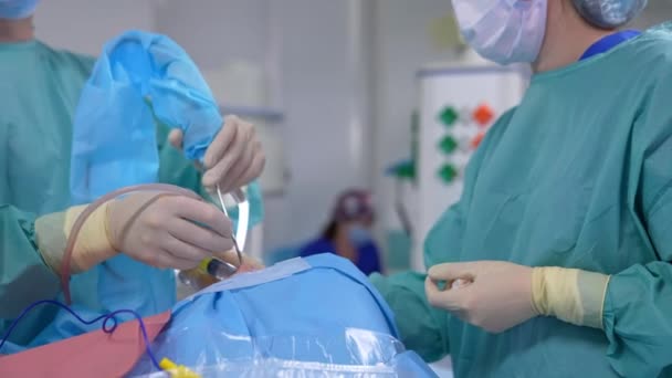 手術室での手術プロセス 医師とアシスタントは 医療機器を使用して患者の顔にマイクロ手術を行います — ストック動画