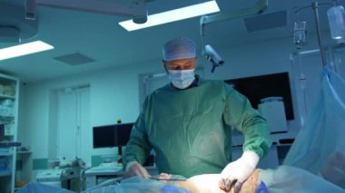 Plastik doktor, tıbbi aletlerle yağ aldırma prosedürü uyguluyor. Doktor ameliyat masasında yatan bir hastanın karnından yağ topluyor. Mavi arkaplan.
