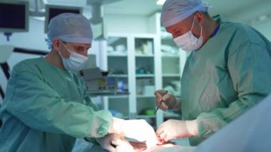 Uzmanlar tarafından estetik ameliyat. Tıp üniformalı doktorlar cerrahi aletler kullanarak ameliyat yaparlar. Ameliyathanede tıp uzmanının işi..