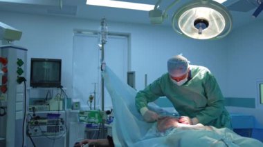 Anestezi altındaki bir hastaya yağ aldırma. Plastik doktor karnından cerrahi aletlerle yağ pompalıyor. Klinikte abdominoplasti.