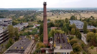 Kırsaldaki eski fabrika binaları. Terk edilmiş santralde büyük tuğla boru. Yok edilmiş depoları olan büyük bir bölge. Hava görünümü.
