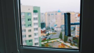 Yüksek bir şehir binasının üst katındaki camları fırçala. Şehir dışından plastik pencereyi temizlemek. İçeriden görüntüle.