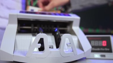 Bankada 50 Euro 'luk banknotlar sayılıyor. Elektronik sayma makinesi kağıt para hesaplamaları yapıyor. Avro banknotlarını sayan bir adamın eli..