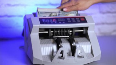 Bankadaki finansal işlemler için elektronik ekipman. Bir kadının eli sayım makinesine kağıt para koyuyor..