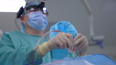 Ameliyat sırasında cerrah ve asistan. Cerrahi aletlerle ameliyat yapan bir hemşireyle birlikte profesyonel doktor. Aşağıdan görüntüle.
