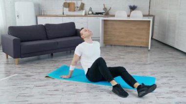 Adam içeride bir paspasın üzerinde rahatlıyor. Evdeki sıkı çalışmadan sonra paspasın üzerinde oturan genç adam. Karantina sırasında spor.