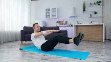 Adam evde fiziksel egzersiz yapıyor. Genç adam karantina sırasında modern mutfakta paspas üzerinde pratik yapıyor. Evde spor..