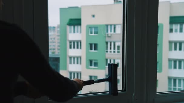 人类用刷子擦窗户和挤压水 男工在公寓里洗玻璃 通过干净的窗户看到一些公寓的背景 持家家务劳动 — 图库视频影像