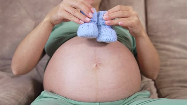 怀孕女孩的贝莉 未来的母亲裸着肚子玩针织婴儿袜 怀孕期间的健康概念 后续行动 — 图库视频影像
