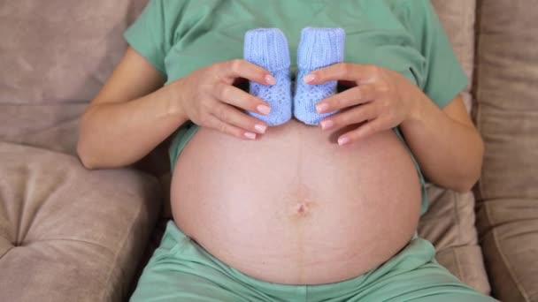 未来的妈妈爱抚她的大肚子 蓝色的针织袜子放在裸胃上 让孕妇感到不舒服 妇女健康和人的概念 产前护理 — 图库视频影像