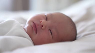 Komik çocuk. Sevimli yeni doğmuş bebek uyuyor ve yatakta esniyor. Evde güzel bir bebek var. Yakın plan..