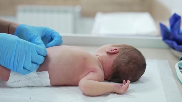 病院のテーブルの上に生まれた赤ん坊 生まれた後 乳児を見下ろす無菌手袋の医師の手 インファンシー コンセプト — ストック動画