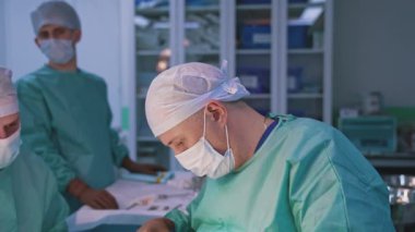 Modern klinikte estetik ameliyat yapan bir grup cerrah. Üniformalı bir grup sağlık çalışanı bir hastaya ameliyat yapıyor..