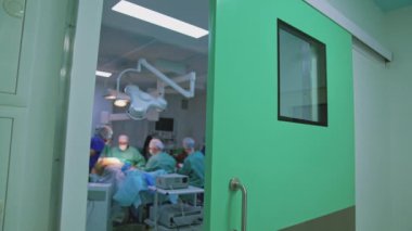 Modern klinikte estetik ameliyat yapan bir grup cerrah. Üniformalı bir grup sağlık çalışanı bir hastaya ameliyat yapıyor..