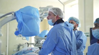 Bir grup doktor bir hastaya ameliyat yapıyor. Ameliyathanede çalışan tıp üniformalı ve maskeli cerrahlar..