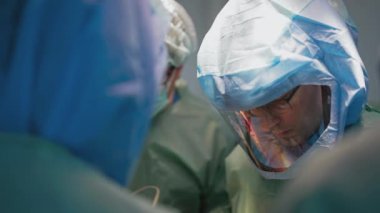 Ameliyathane ve ameliyat devam ediyor. Tıbbi ekip, parlak modern ameliyathanede cerrahi operasyon gerçekleştiriyor.